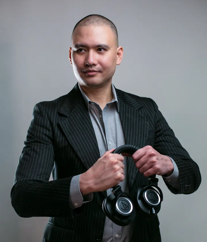 DJ Selphi in a pinstripe suit holding headphones