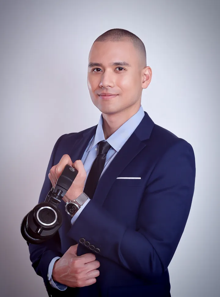 DJ Selphi in a navy suit holding headphones